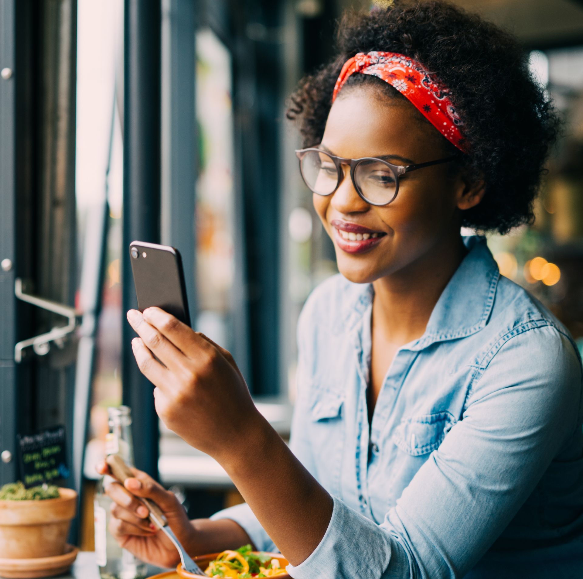A woman is sitting at a table looking at her phone.