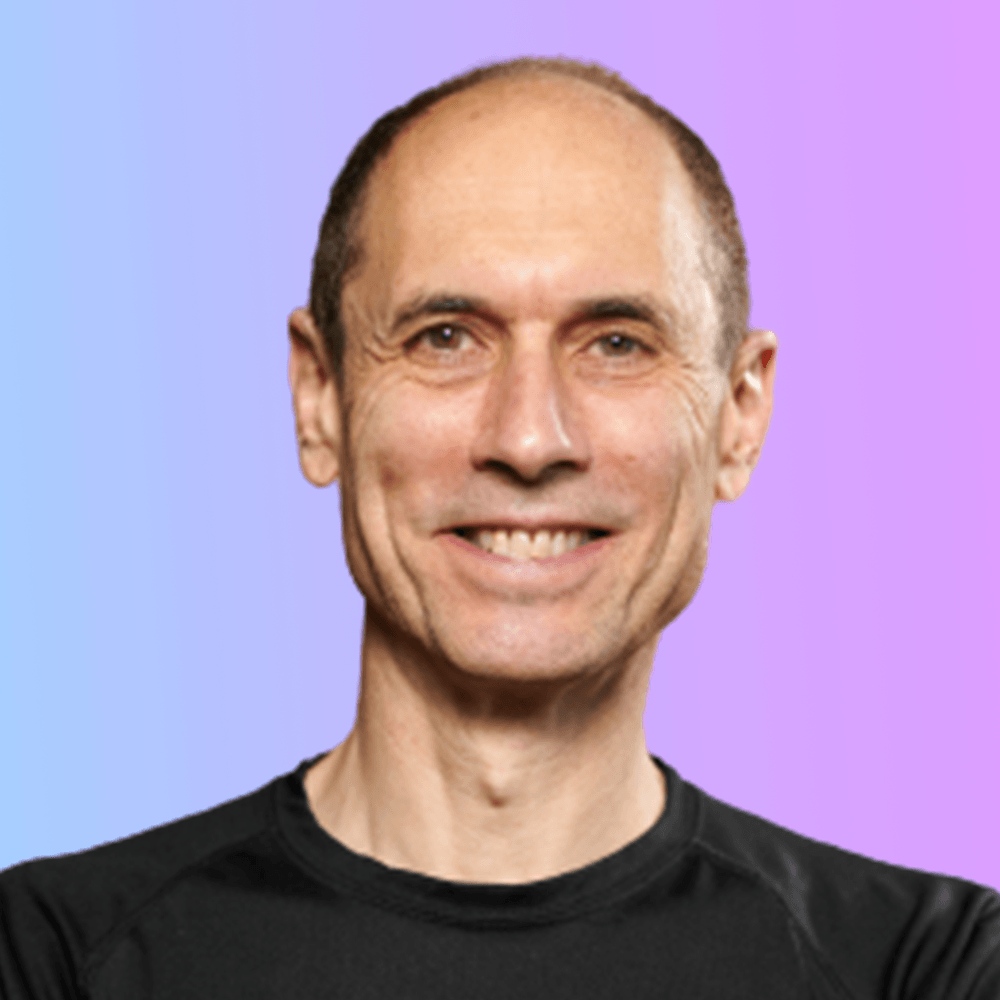 A man in a black shirt is smiling with his arms crossed