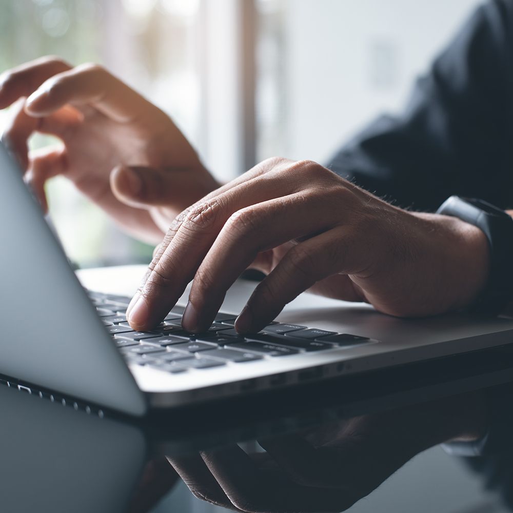 A close up of a person 's hands typing on a laptop