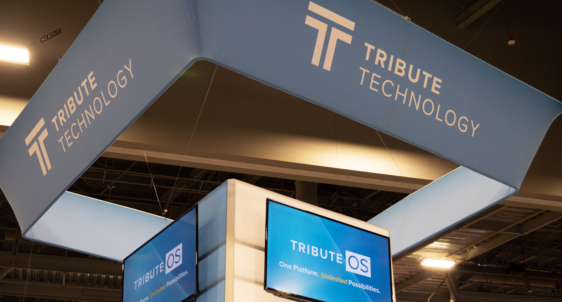 A tribute technology sign hangs from the ceiling of a room.