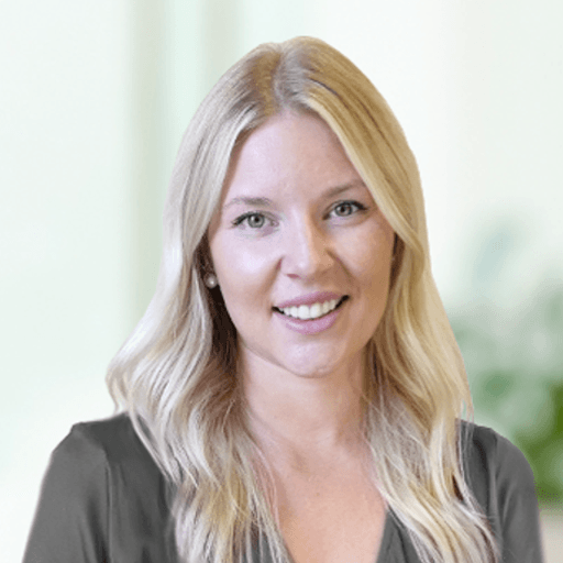 A woman with blonde hair is smiling and wearing a gray shirt.
