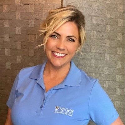 A woman in a blue polo shirt is smiling for the camera.