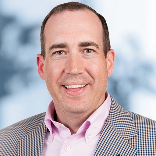 A man in a suit and pink shirt is smiling for the camera.