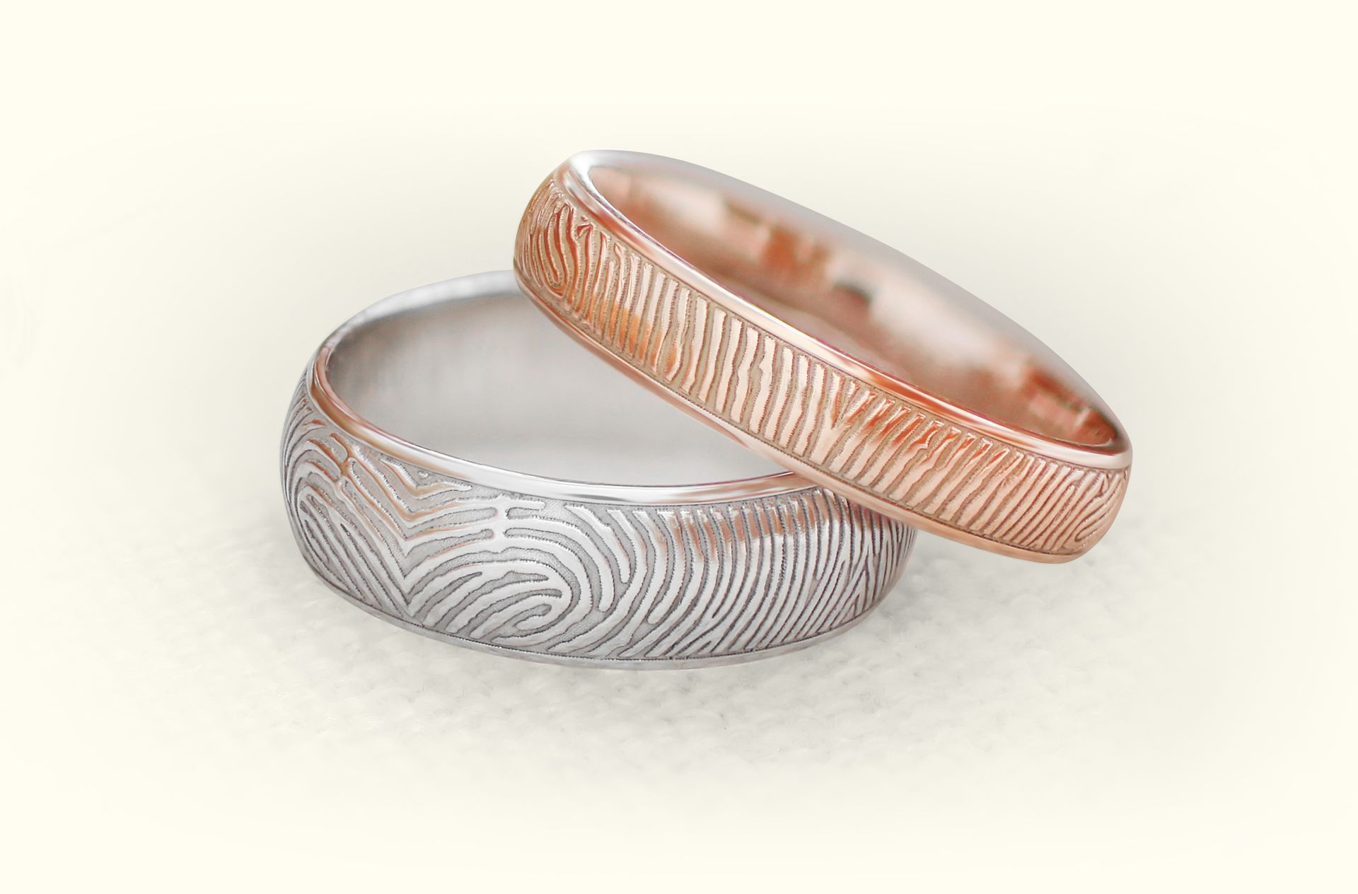 A pair of wedding rings with fingerprint patterns on them.