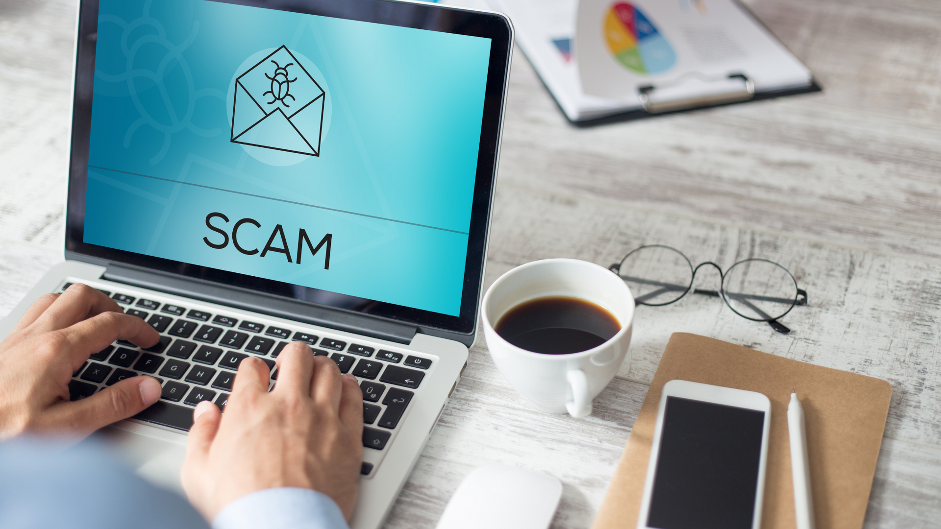 A person is typing on a laptop computer with the word scam on the screen.