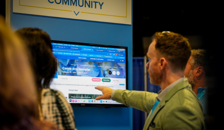 A man is pointing at a computer screen at a conference.