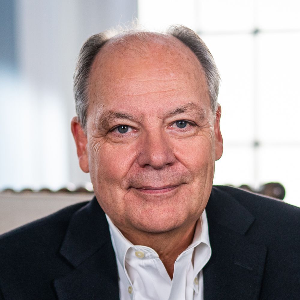 A man in a suit and white shirt is smiling for the camera.