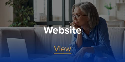 A woman is sitting on a couch looking at a laptop computer.