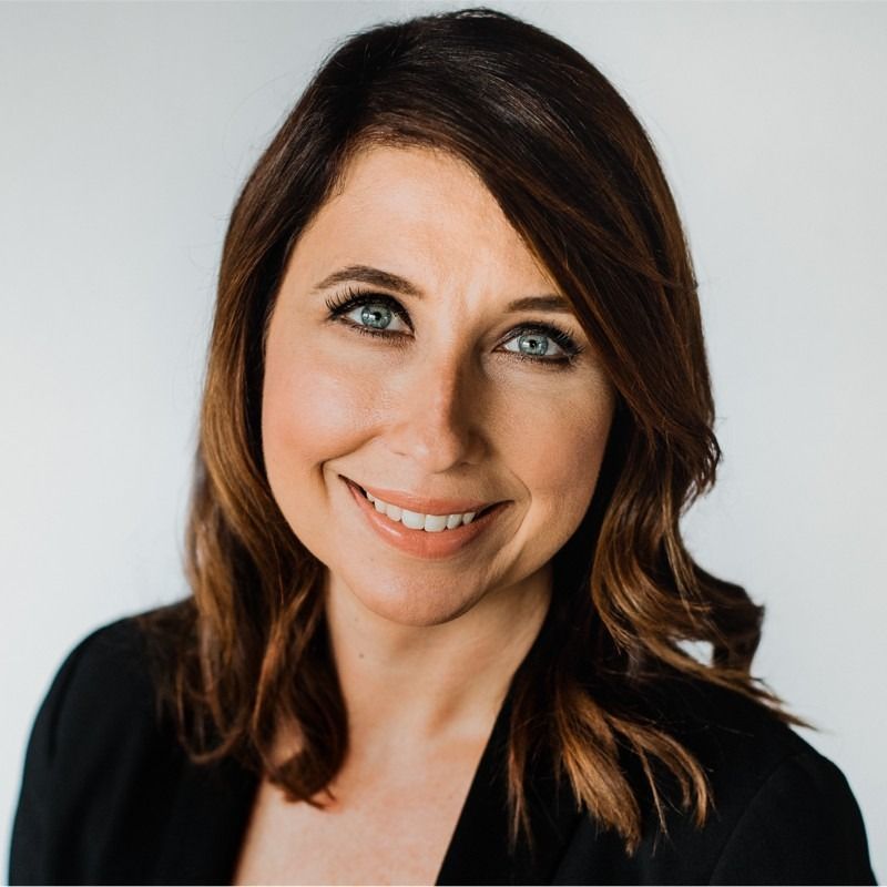 A woman in a black jacket and white shirt is smiling for the camera.