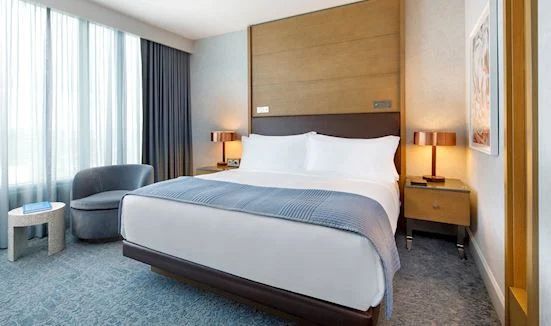 A hotel room with a king size bed and a chair.