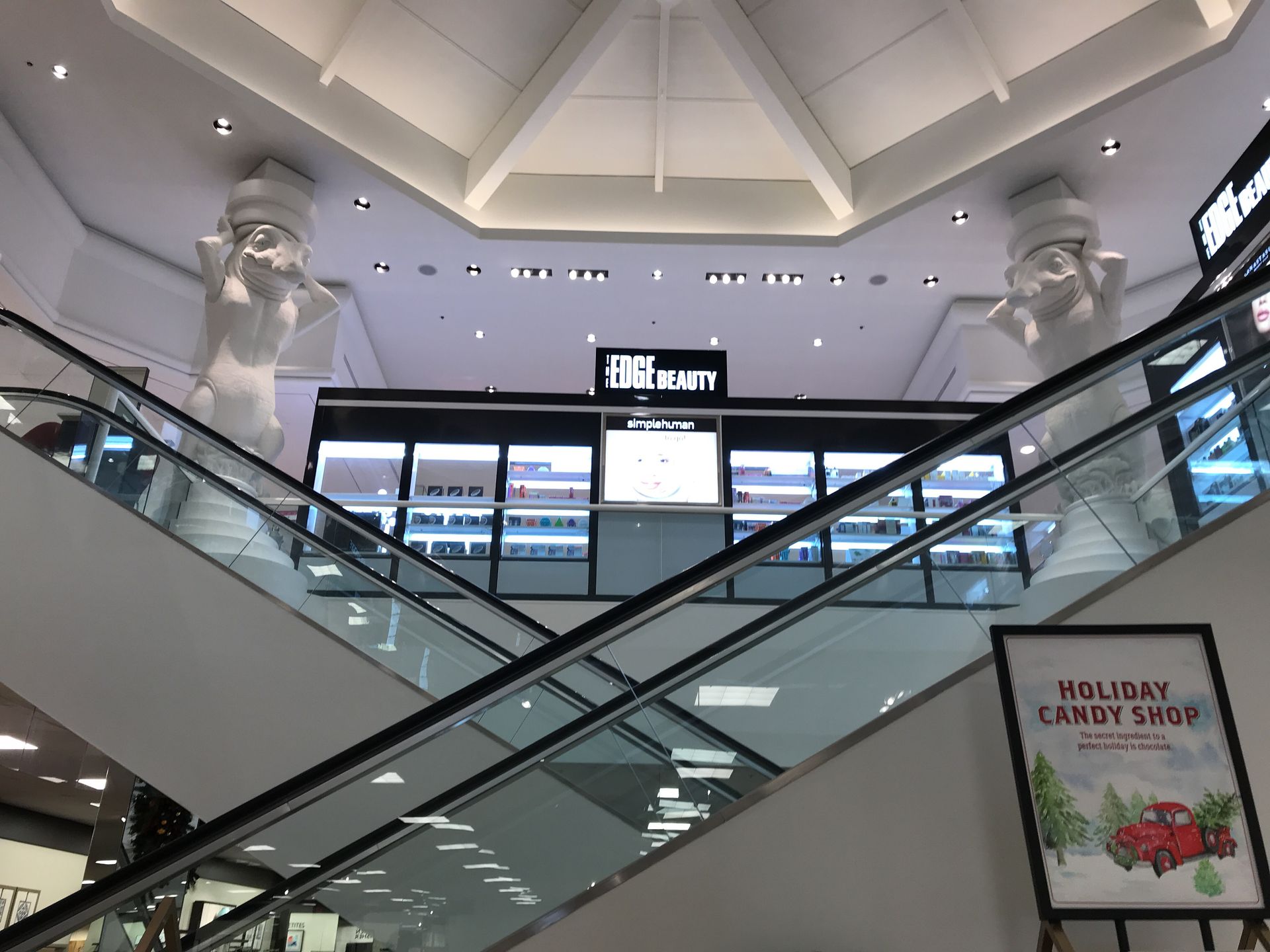 An escalator in a mall with a sign that says walgreens candy shop
