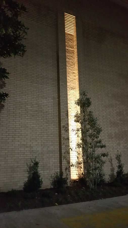 A tall brick building with a light on the side of it at night.