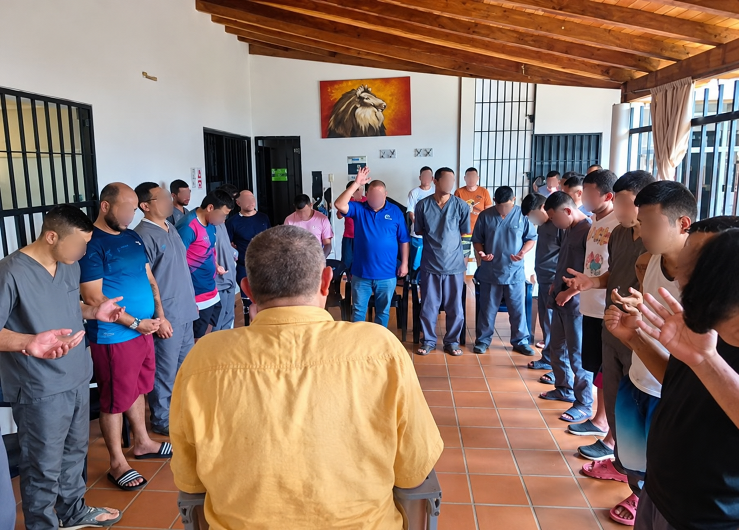 Grupo de personas de pie en un pasillo, aplaudiendo durante una reunión en un espacio cerrado con techo de madera y suelo de baldosas