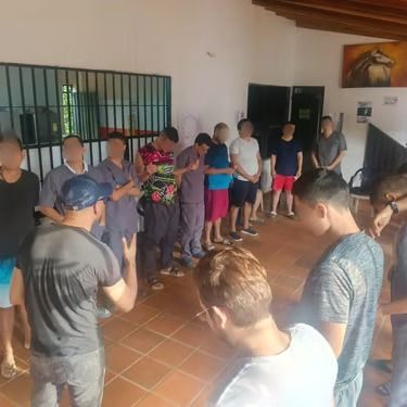 Personas de pie en círculo dentro de un edificio durante una reunión o actividad grupal.
