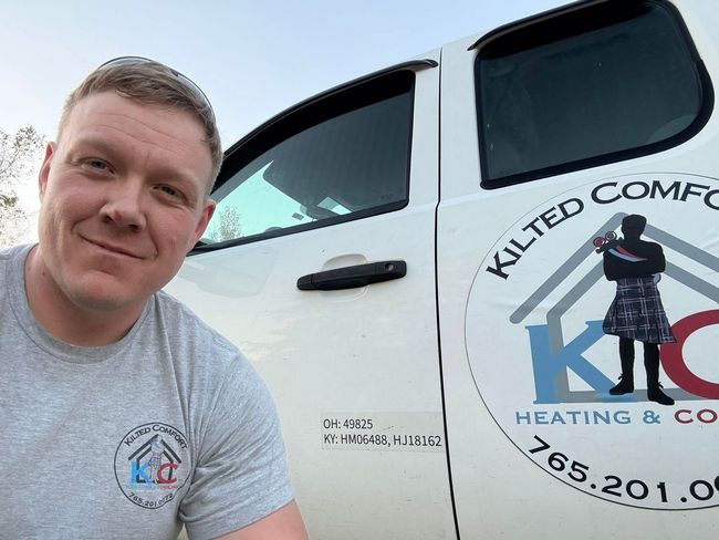 Smiling man beside white service truck with heating and cooling company logo