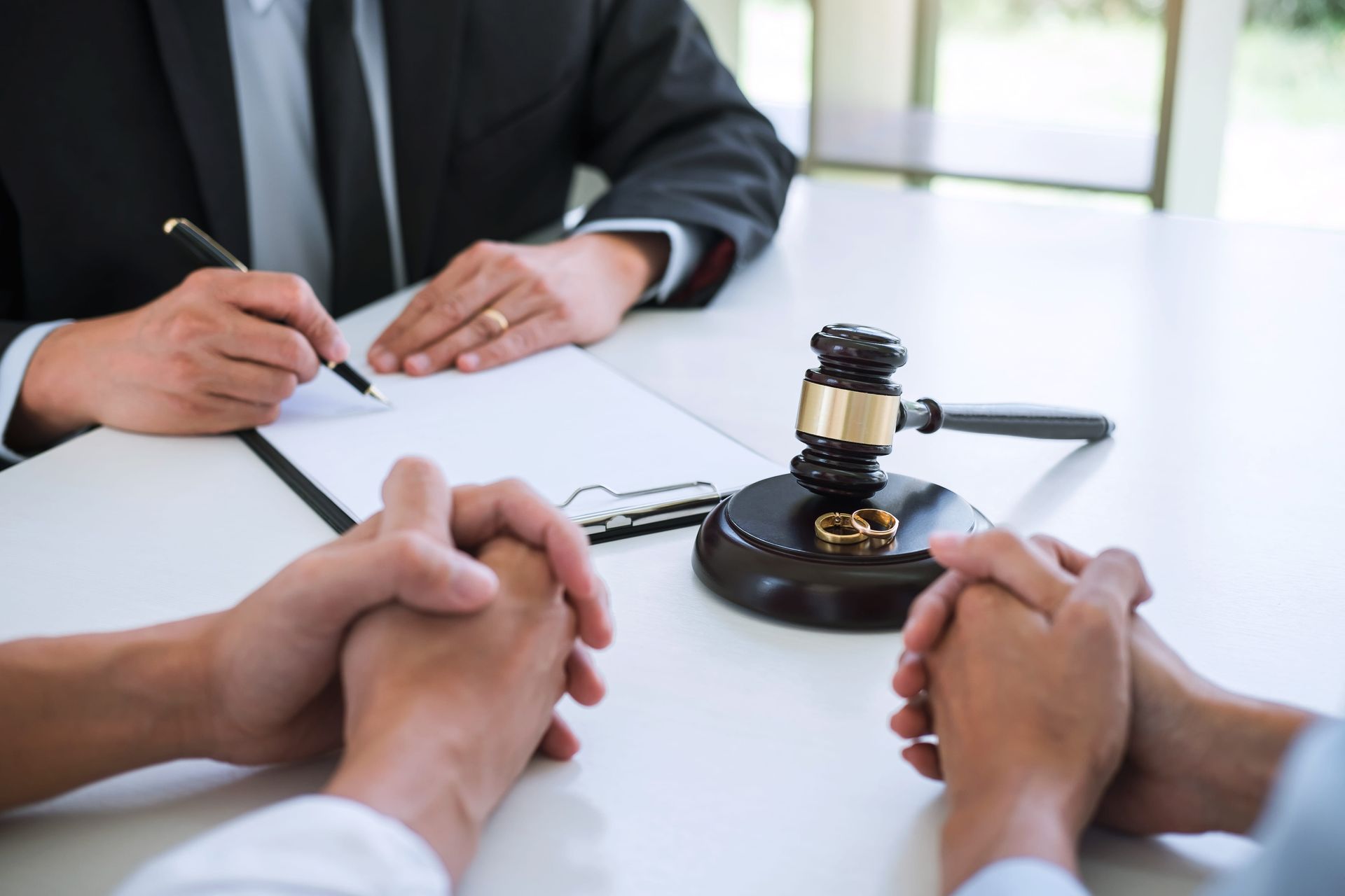 A judge is sitting at a table with a couple of people. and wedding rings are on the gavel.