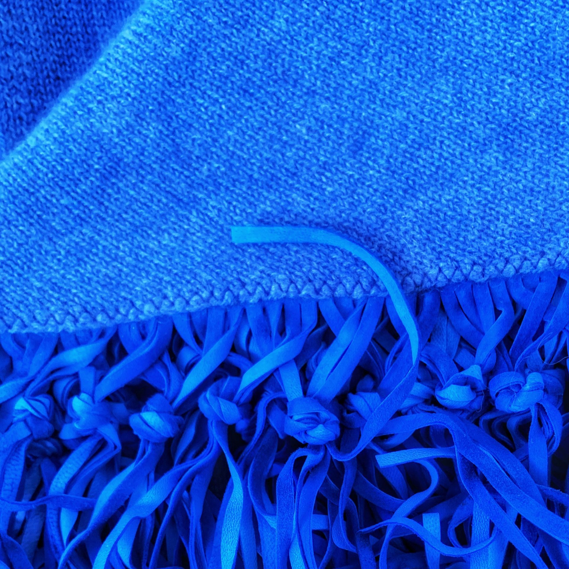 Tessuto blu testurizzato con bordo sfrangiato e primo piano di un filo allentato.