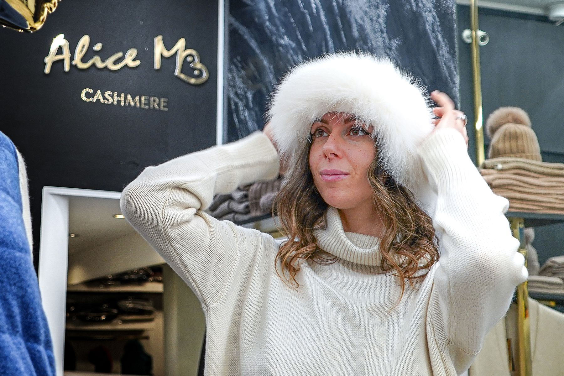 Donna con maglione bianco foderato di pelliccia con cappuccio a una presentazione di cashmere di Alice M.