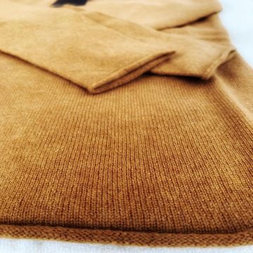 Tessuto beige piegato e sovrapposto a una coperta marrone dalla trama ruvida, primo piano.