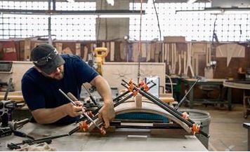 A man is working on a piece of wood in a workshop.