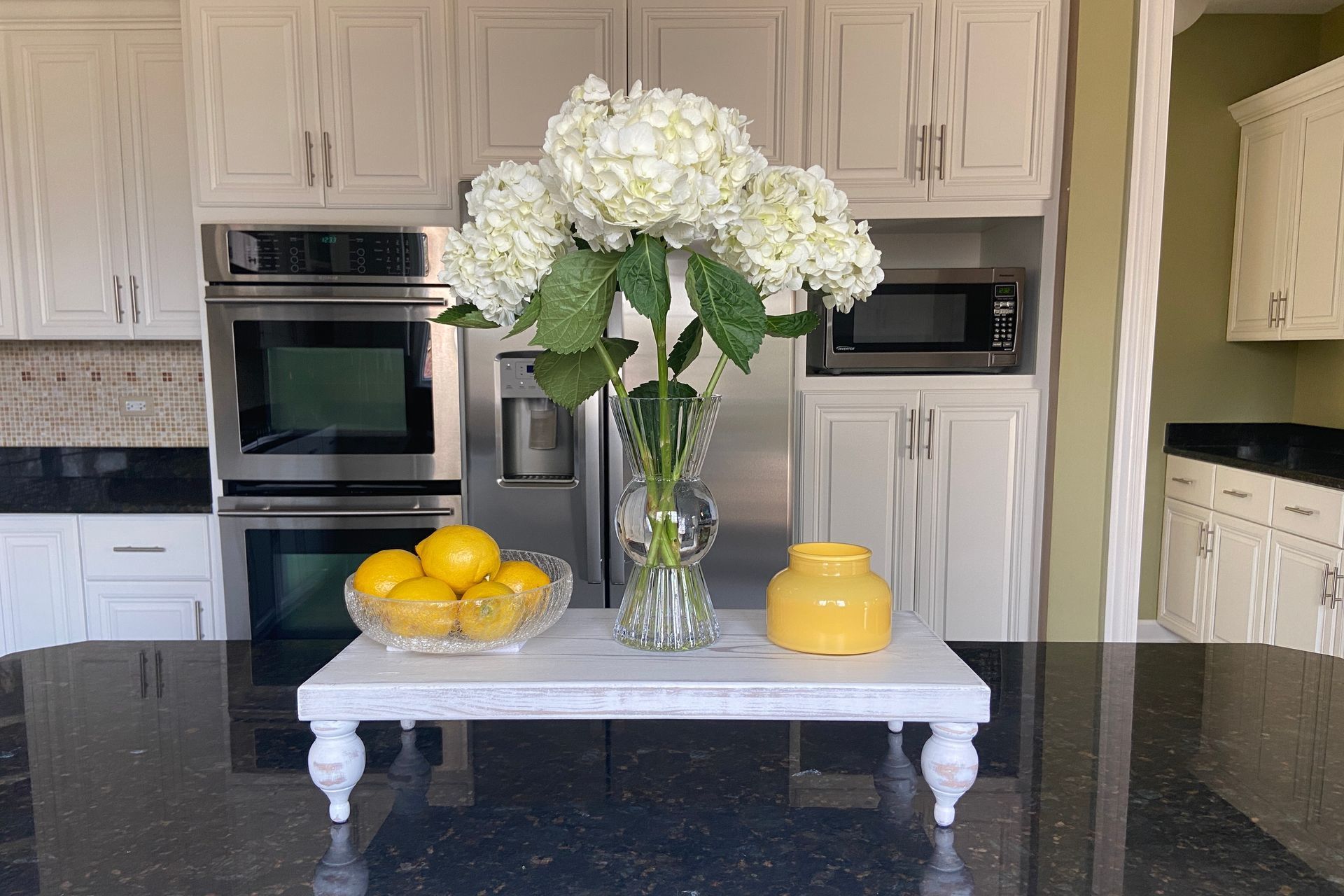 A kitchen counter with a vase of flowers and lemons on it.