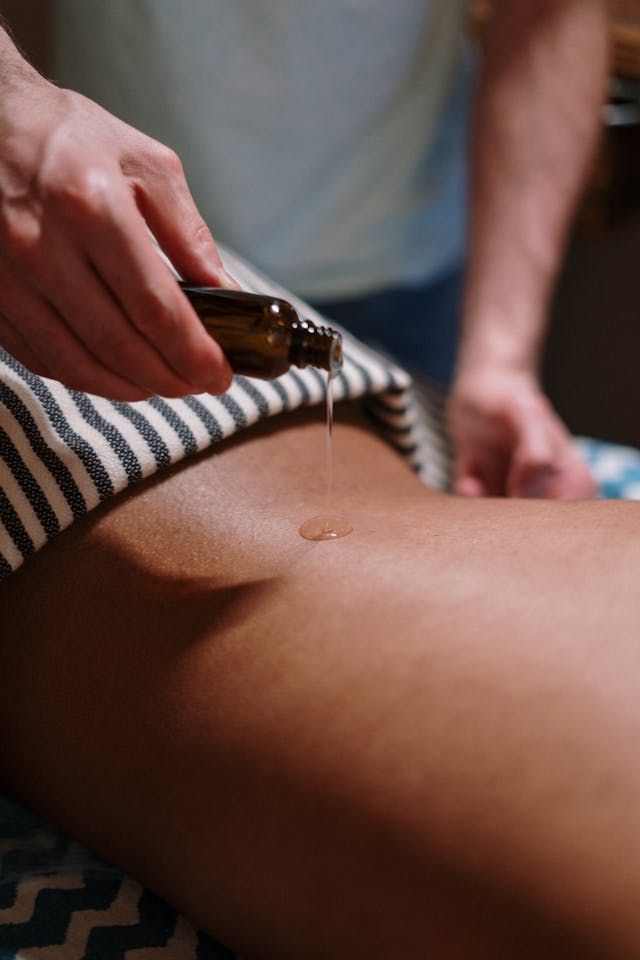 Une personne reçoit un massage avec de l'huile sur le dos.