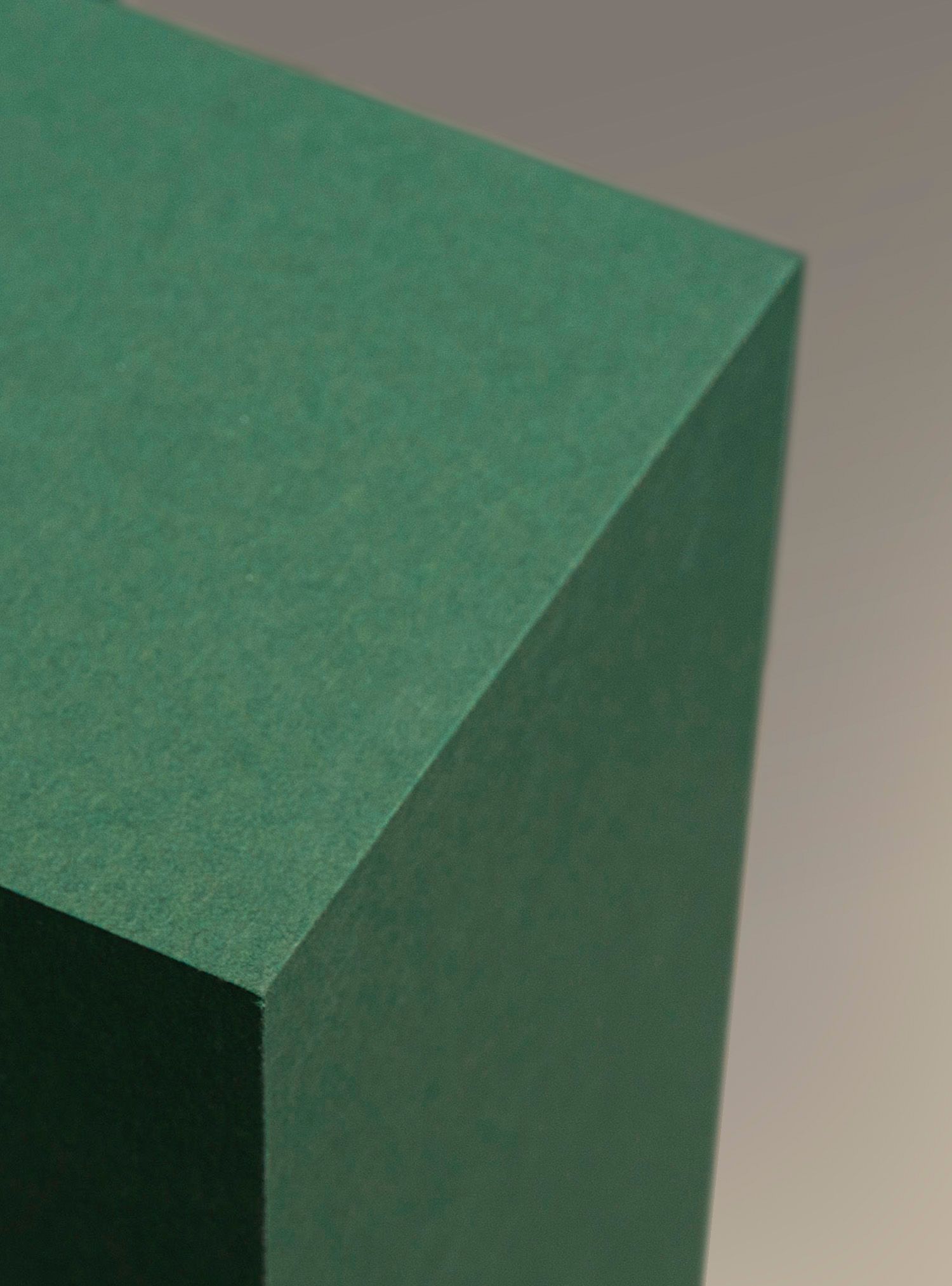 Close-up of a green, rectangular prism with a textured surface, showcasing its edges.