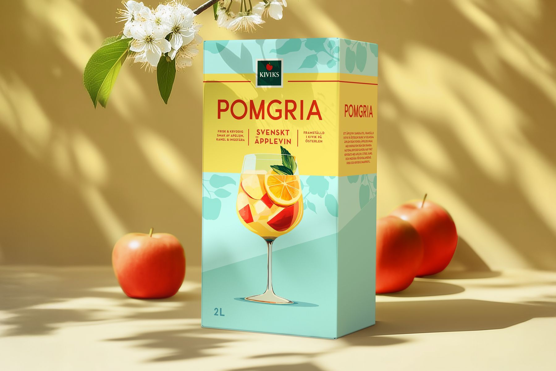 Box of Pomgria wine with fruit in a glass and apples, against a light yellow background.