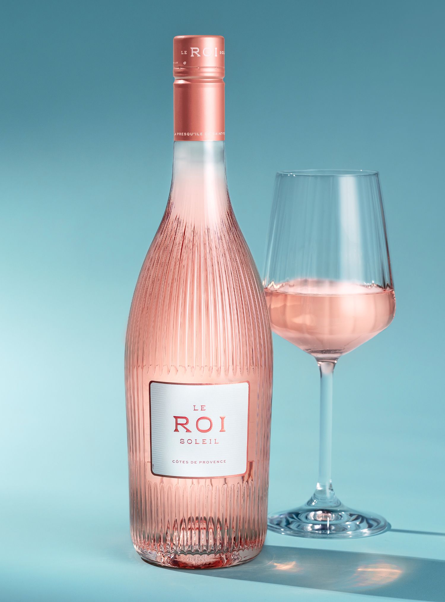 Bottle of rosé wine with a glass, both lit with soft light.