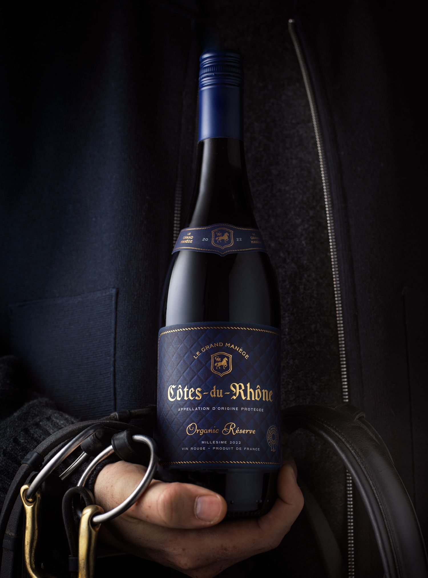 Person holding a dark blue wine bottle, label reads