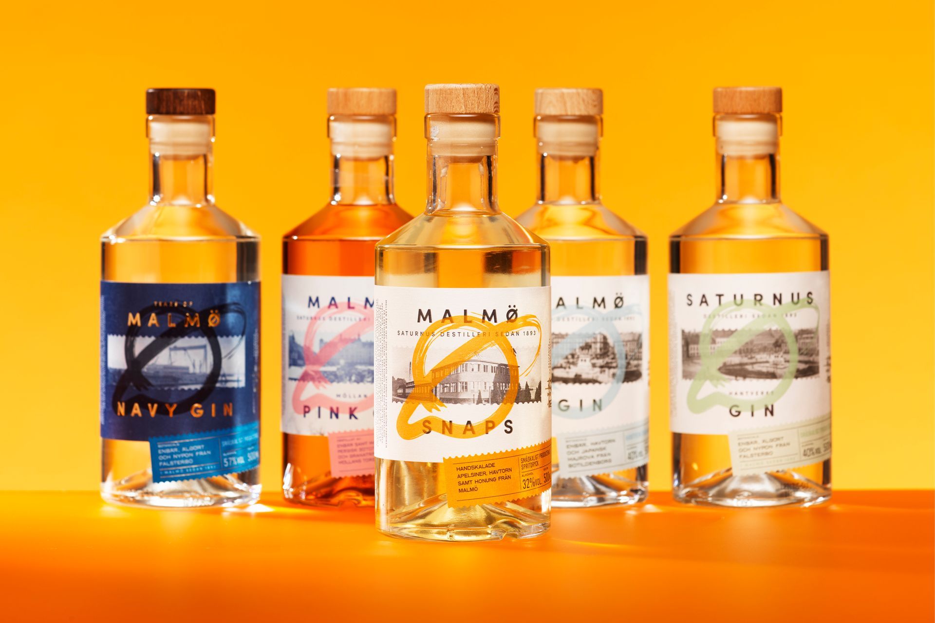 Five bottles of gin with colorful labels against a yellow background.