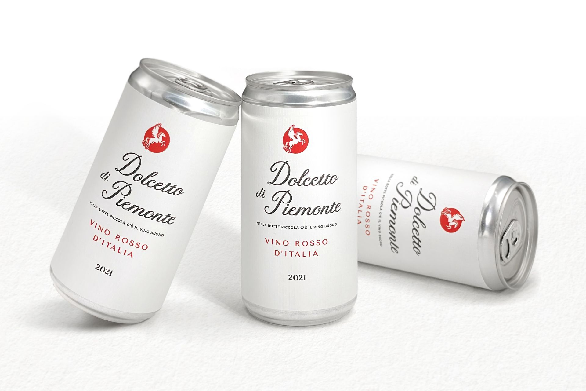 Three white Dolcetto d' Piemonte wine cans with red text, scattered on a white surface.