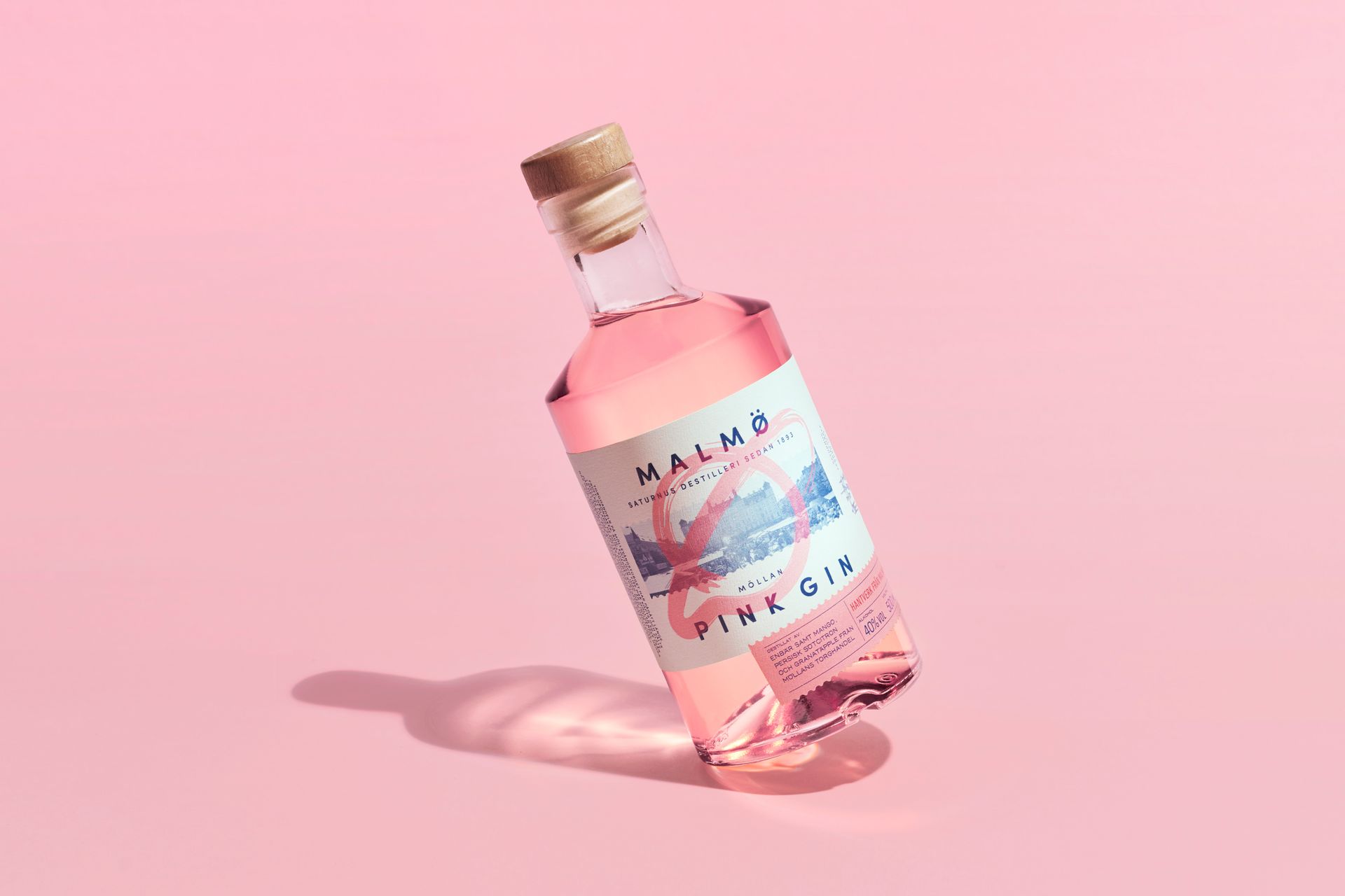 Malmö Pink Gin bottle on a pink background, casting a shadow.