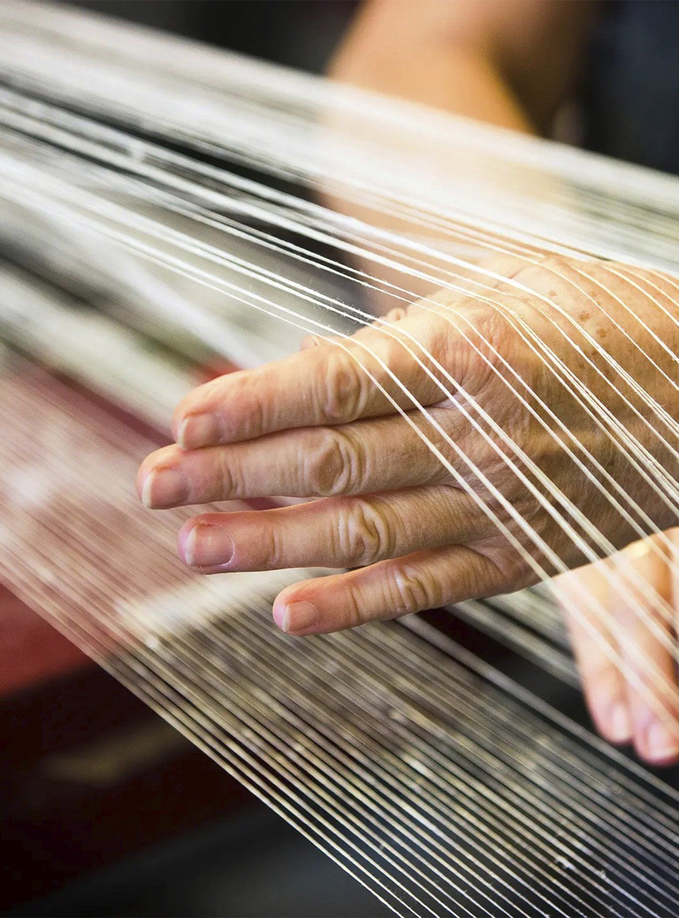 Hand weaving white threads; close-up from Klässbols linneväveri.