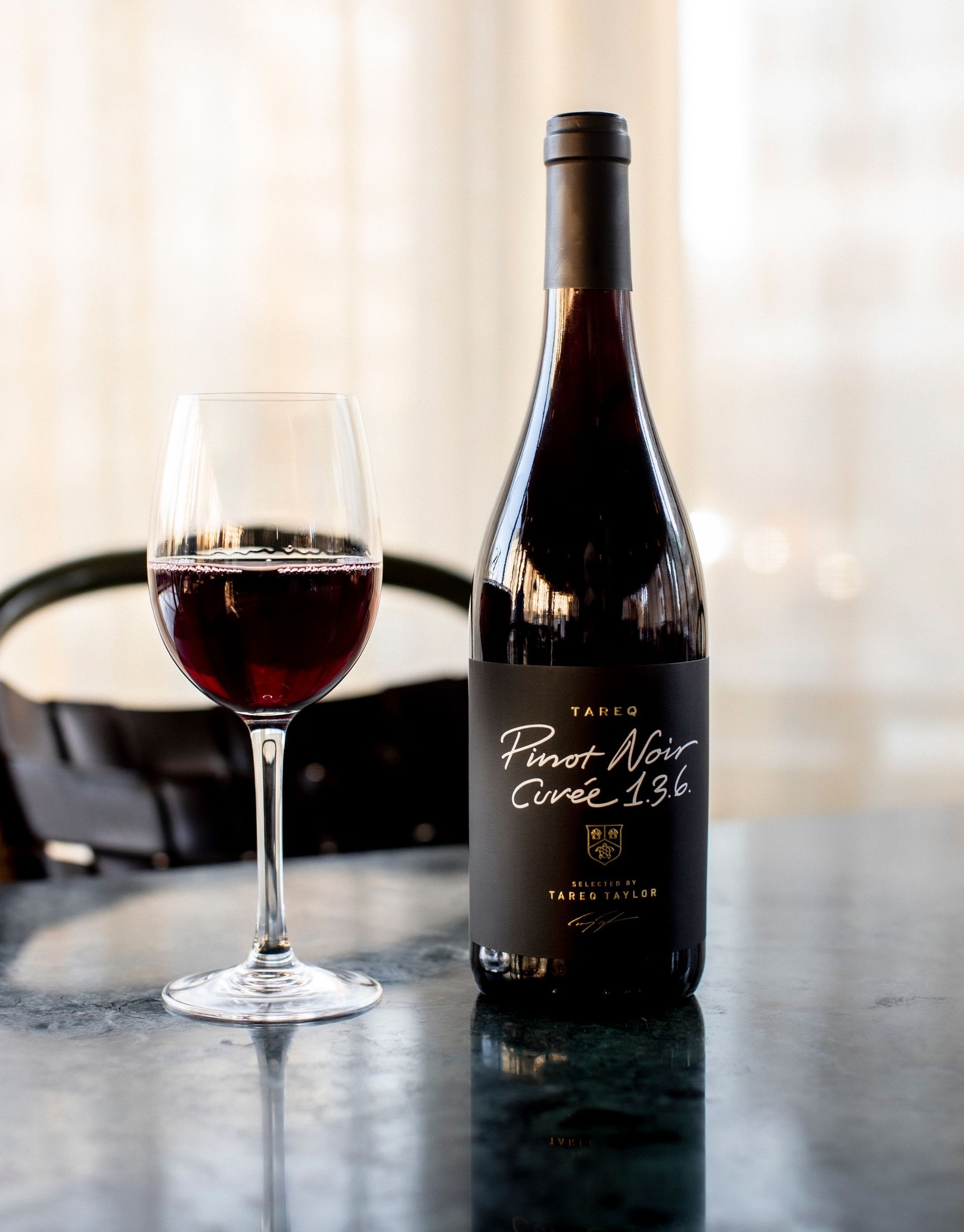 Bottle of red wine and glass filled with wine on a table.