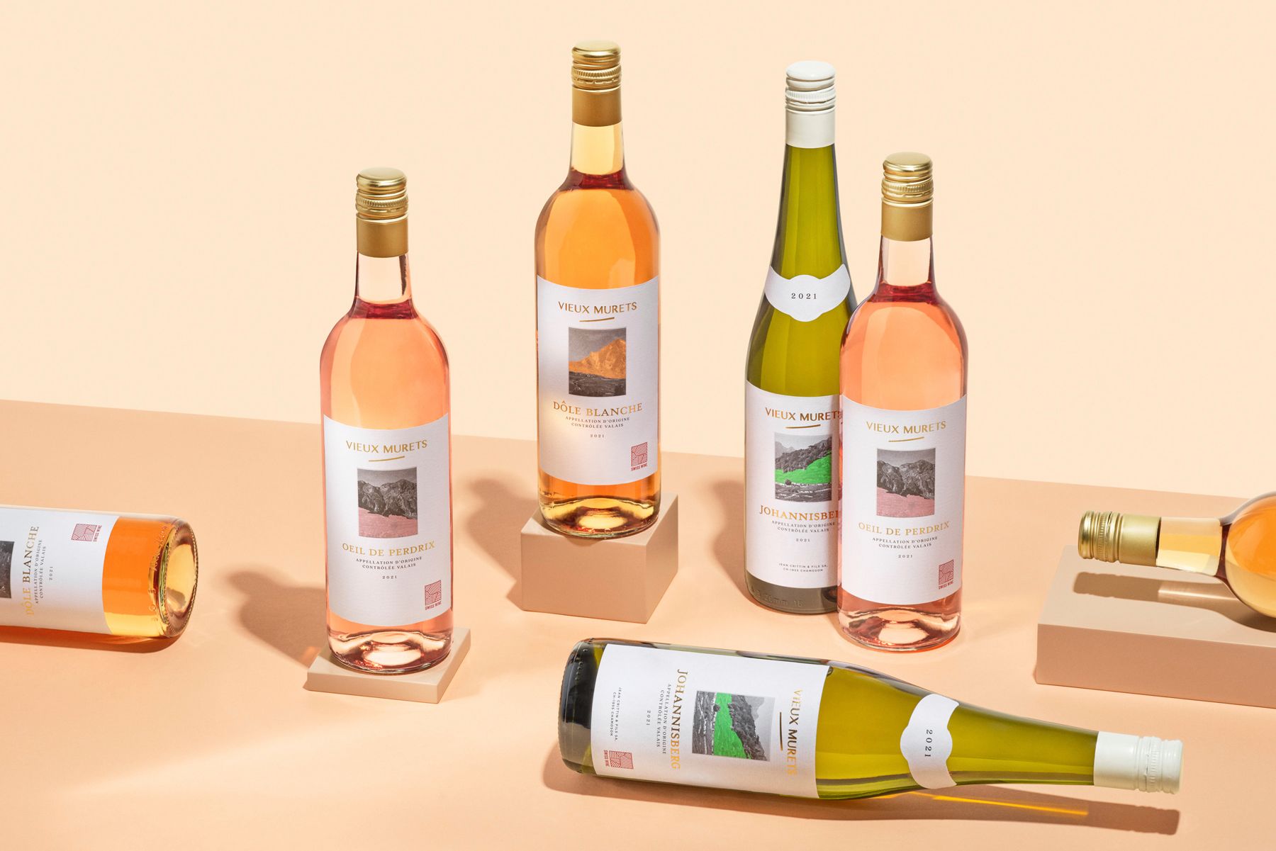 Wine bottles from Denner, Vieux Murets, various colors, on a peach surface, some standing, some lying down.