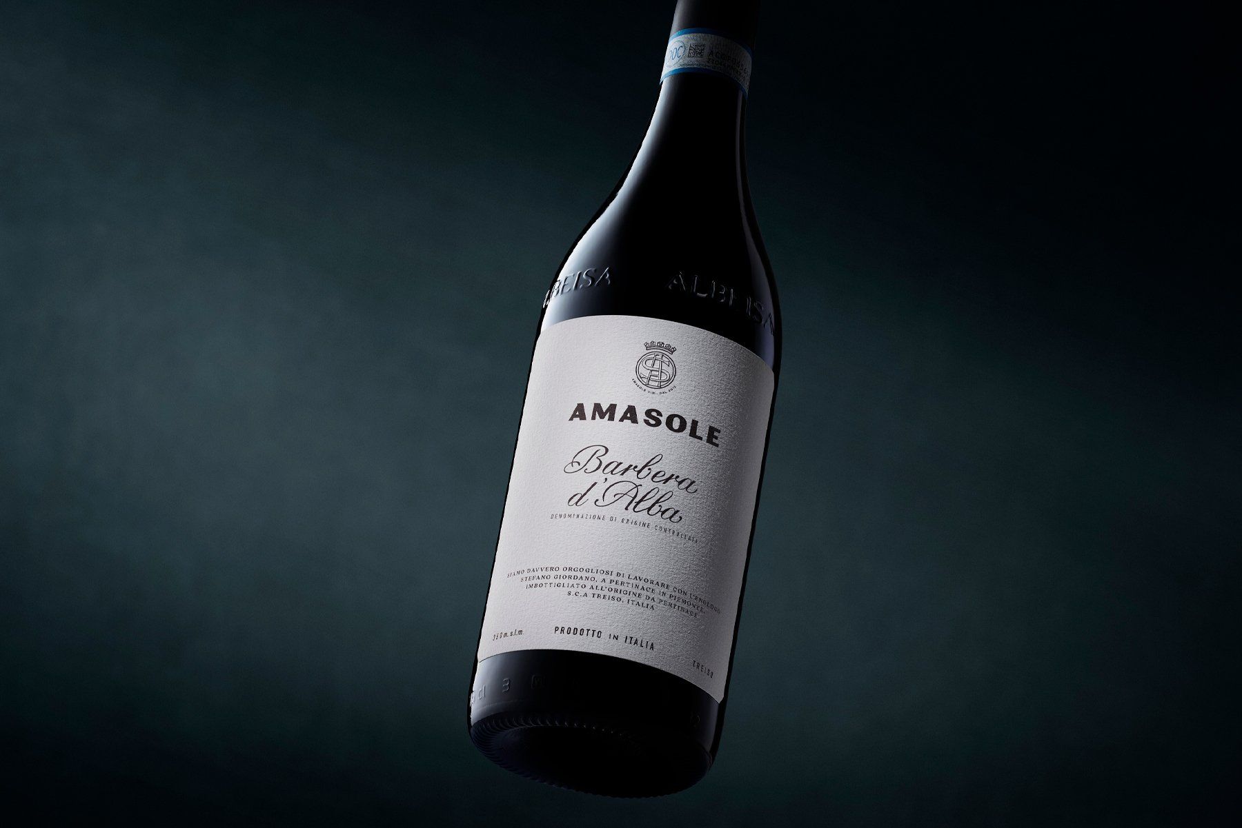 Bottle of Amasole wine with white label, angled against a dark background.