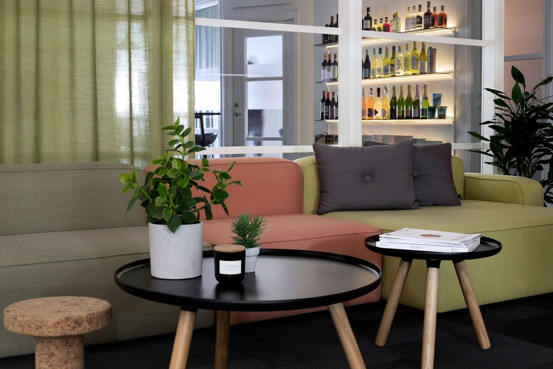 Living room with sofas, round coffee tables, plants, and a bar area in the background.