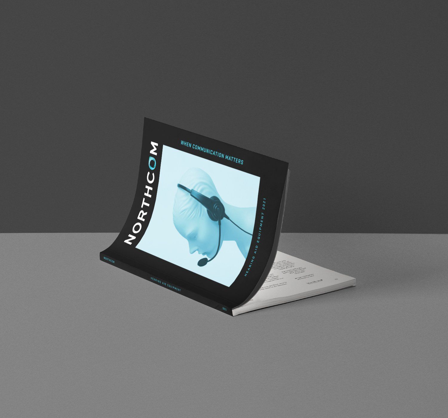 Catalog with a person wearing a headset on the cover, curved open on a gray surface.