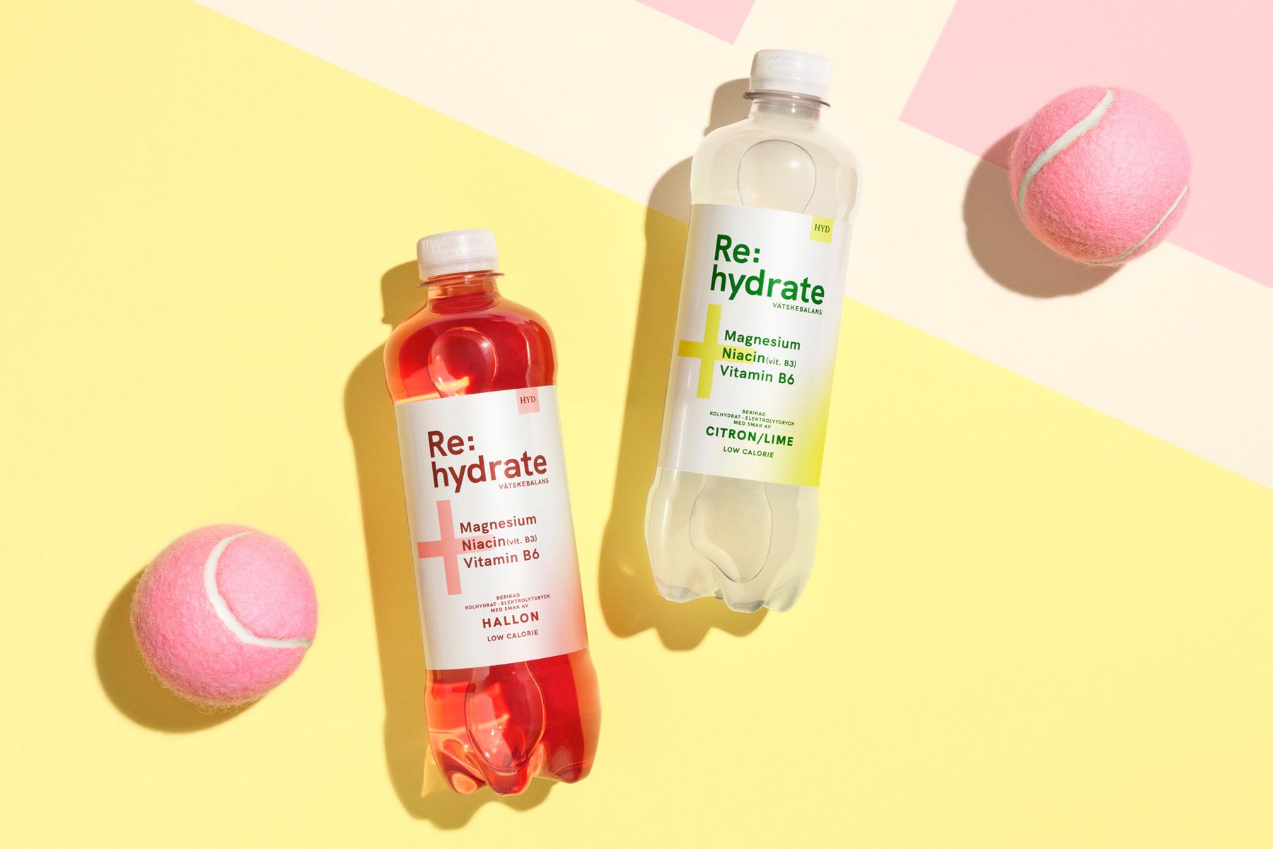 Two bottles of Re-hydrate drinks with tennis balls on a yellow and pink background from Saturnus