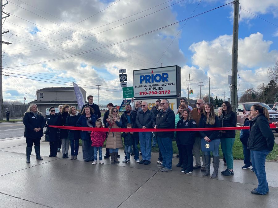 A group of people are standing in front of a sign that says prior.