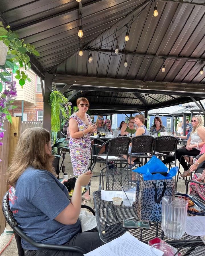 A group of people are sitting at tables under a gazebo