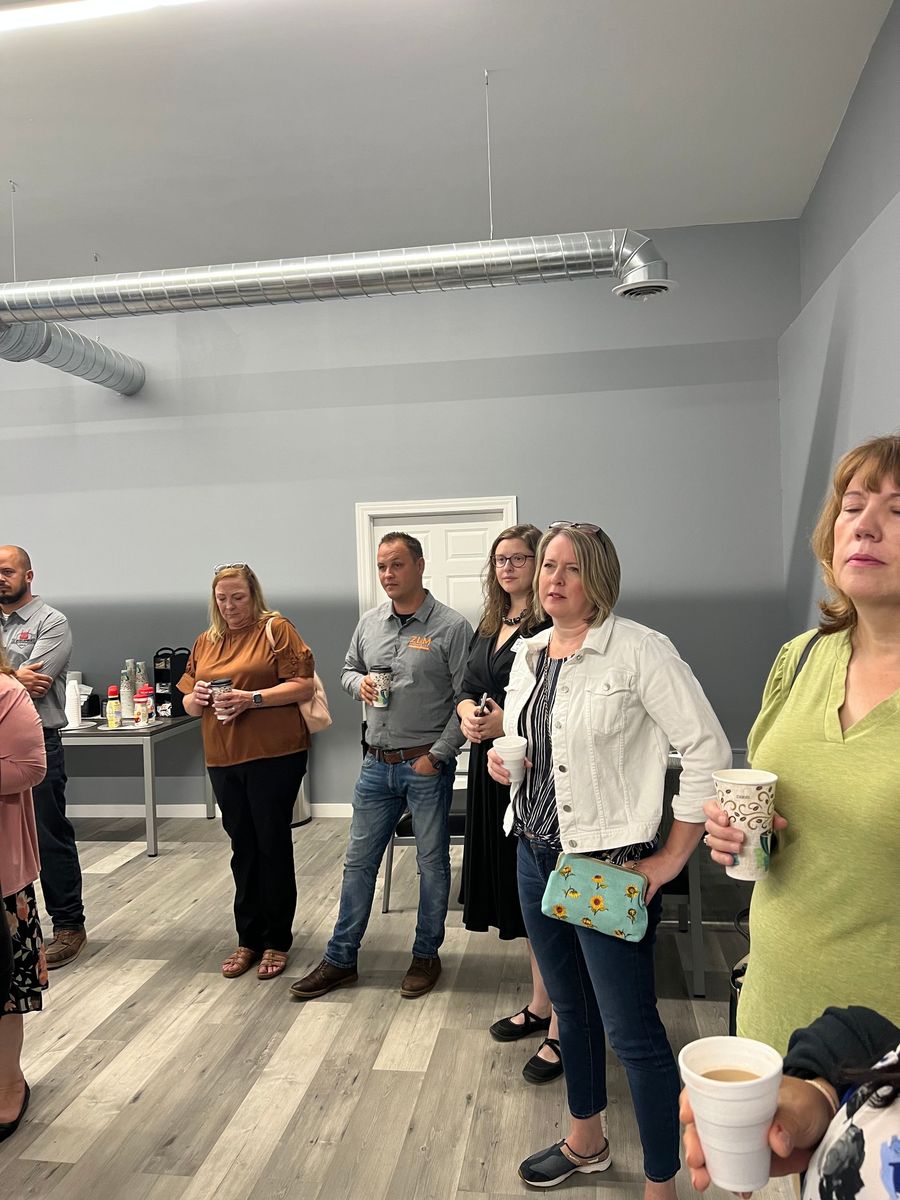 A group of people standing in a room holding cups of coffee