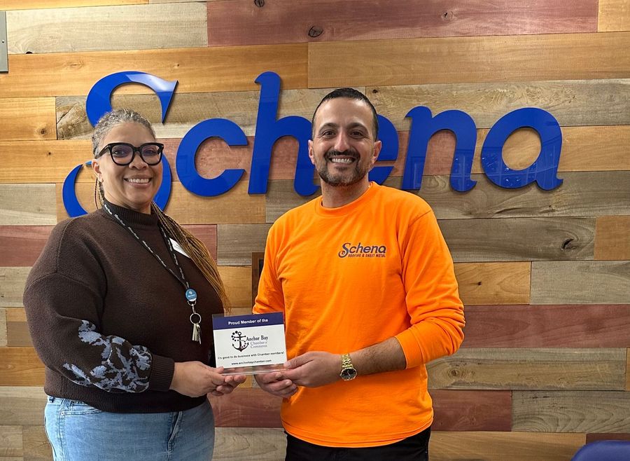 A man and a woman are standing in front of a sign that says schena