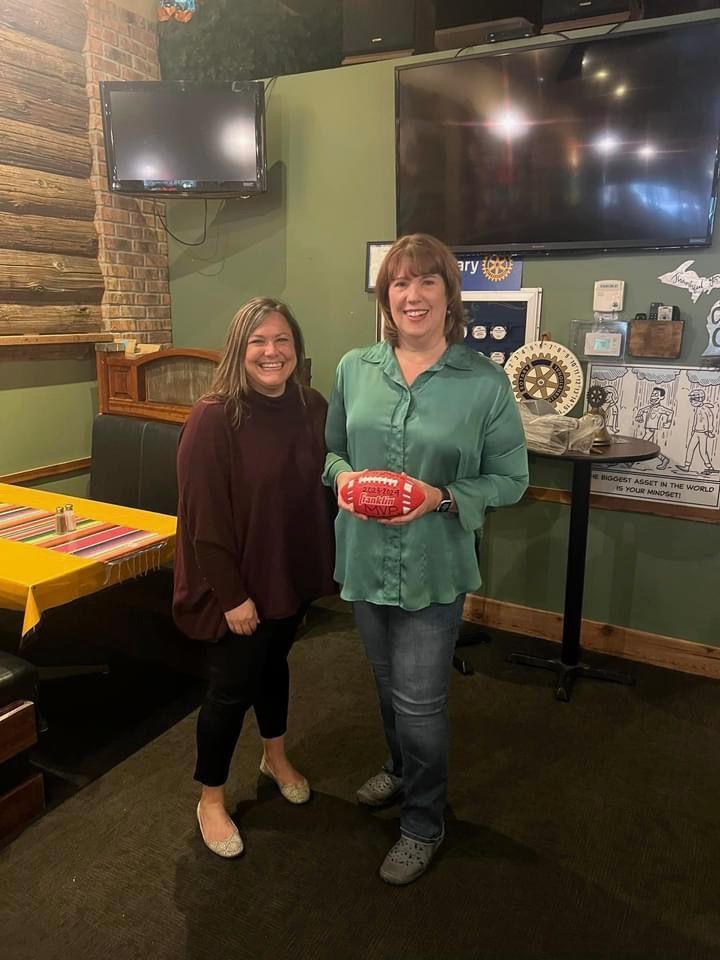 Two women are standing next to each other in a restaurant holding a football.