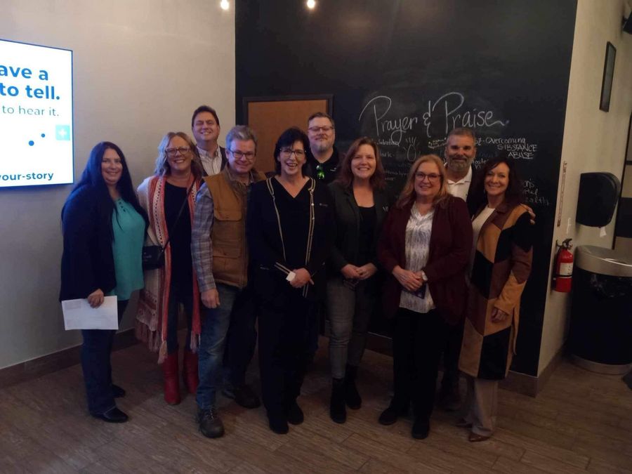 A group of people standing in front of a chalkboard that says 