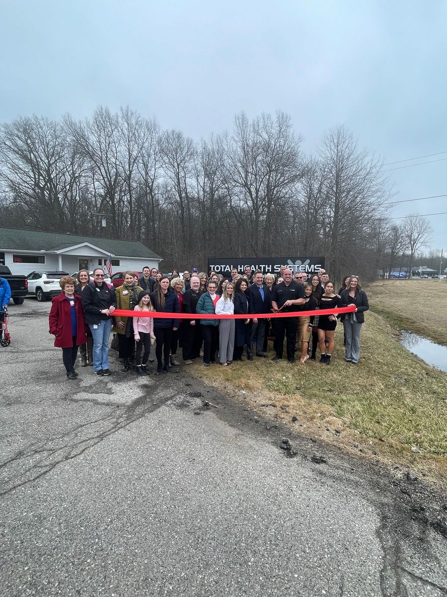 A large group of people are standing in front of a red ribbon.