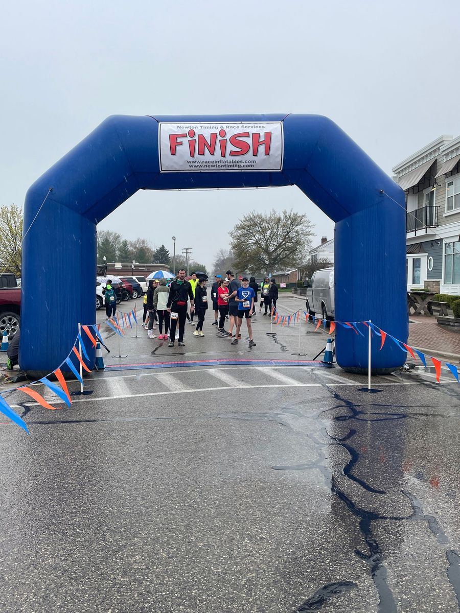 A group of people are walking under an inflatable arch that says finish.