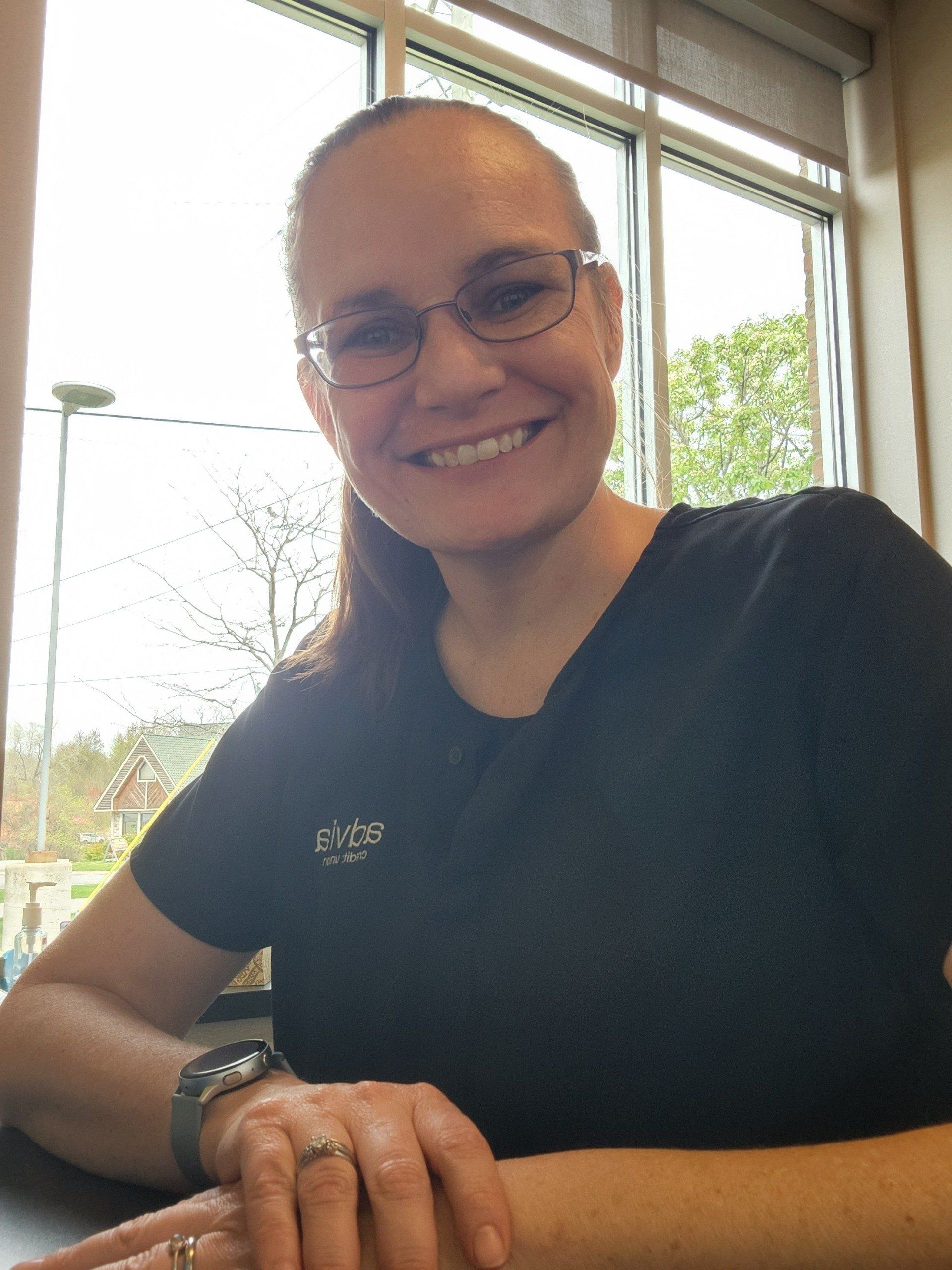 A woman wearing glasses and a black shirt smiles for the camera