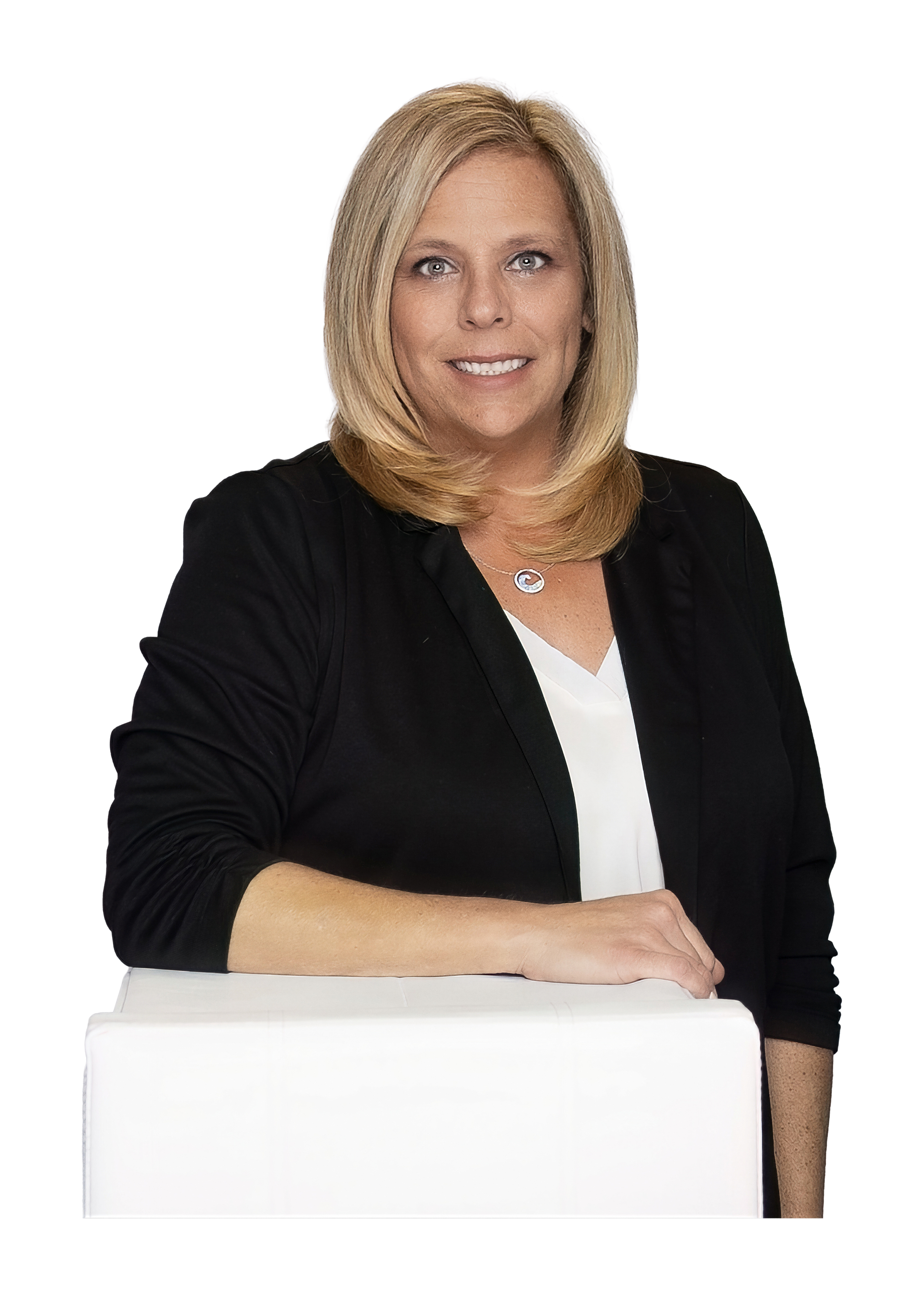 A woman is sitting at a table with her arms crossed and smiling.